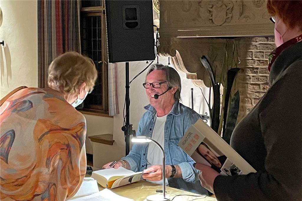 Als Helmut Zierl von der Schule flog und kurz darauf Todesangst hatte Ein Mann signiert ein Buch.
