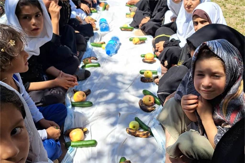 Latifa Saljuki wünscht sich von Herzen Paten für afghanische Schule Kinder sitzen am Tisch, vor ihnen liegt Obst.