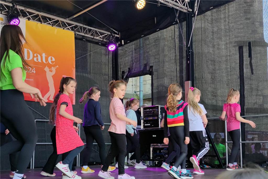 Kinder tanzen und turnen auf einer Bühne.