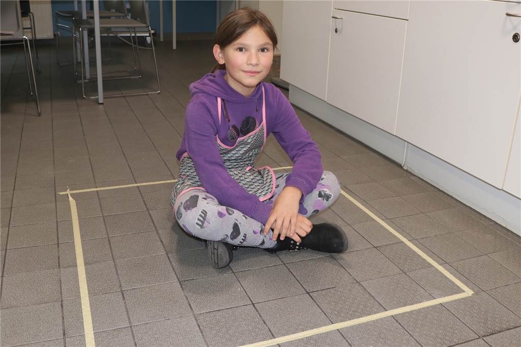 Kinder-Koch-Klub mit Frischkorn-Müsli, Rührei mit Paprika und einem Quadrat auf dem Boden Klara (10) im "Hühnerstall" von einem Quadratmeter. Mit ihren 37 Kilogramm wiegt sie fast soviel wie die rund 20 Hühner, die in der konventionellen Hühnermast auf dieser Fläche erlaubt sind.