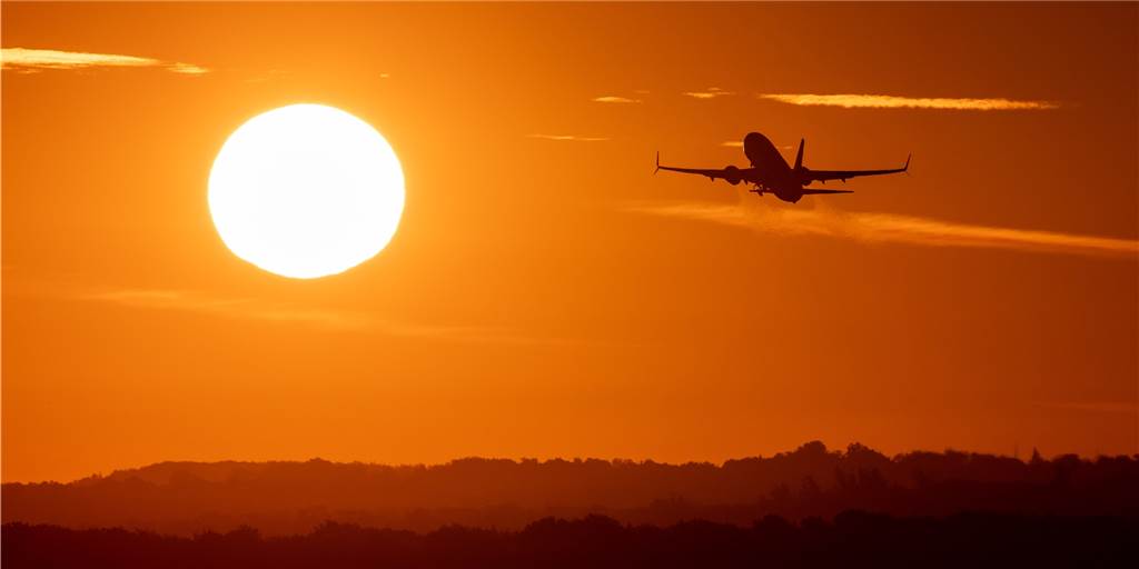 Ein Passagierflugzeug startet in die aufgehende Sonne in Düsseldorf.