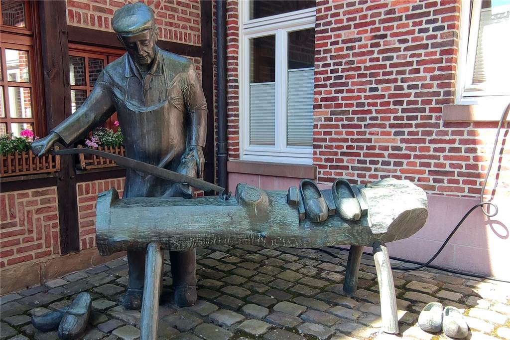 Eine Bronzeskulptur eines Holzschuhmachers.