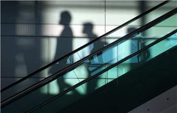Personen auf einer Rolltreppe als Schatten
