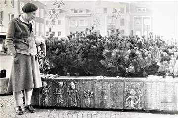 Künstlerin Tisa von der Schulenburg vor dem im Winter begrünten Marktplatz-Brunnen, deren Reliefarbeiten sie entworfen hat (Datum der Foto-Aufnahme unbekannt).