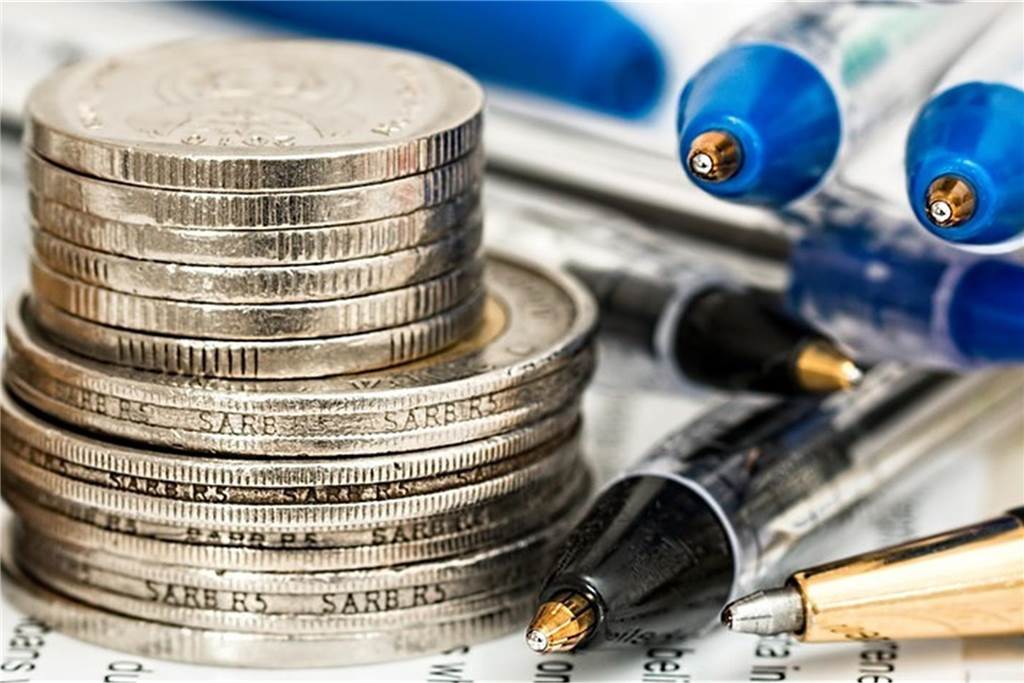 Landwärme insolvent: Hiobsbotschaft für neue Biomethan-Anlage Gestapelte Geldmünzen und Kugelschreiber liegen auf einem Papier