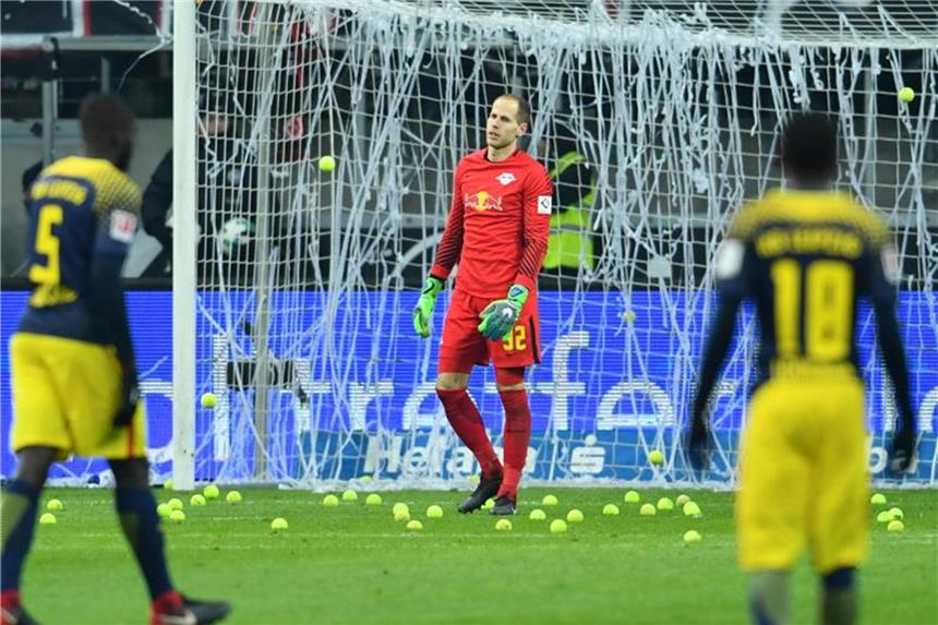 Frankfurt, Wolfsburg und Freiburg mit Geldstrafen belegt Leipzigs Keeper Peter Gulacsi (M) steht zwischen Tennisbällen, mit denen Eintracht-Fans gegen Montagsspiele protestierten. Foto: Uwe Anspach