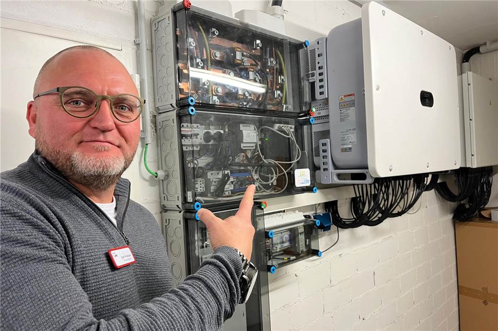 PV-Anlage: Bürger-Genossenschaft bringt AWO-Seniorenzentrum neue Energie Ein Mann zeigt mit einem Finger auf eine Stromsteuerungsanlage in einem Keller.