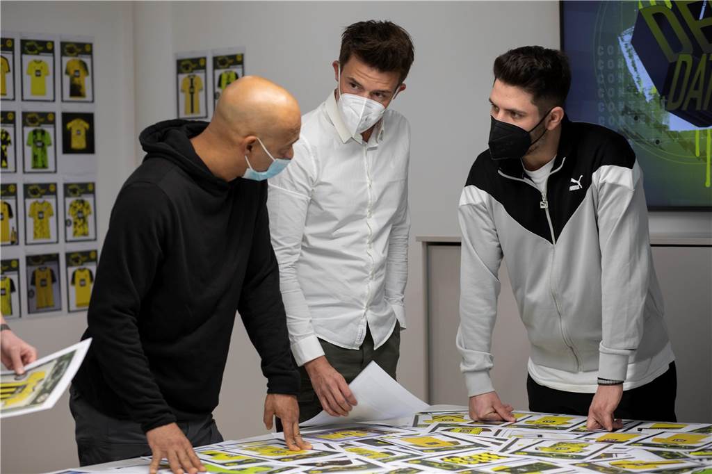 BVB-Heimtrikot für die Saison 2023/2024: Gewinner von „Design datt Ding“ steht fest Drei Männer sprechen miteinander.