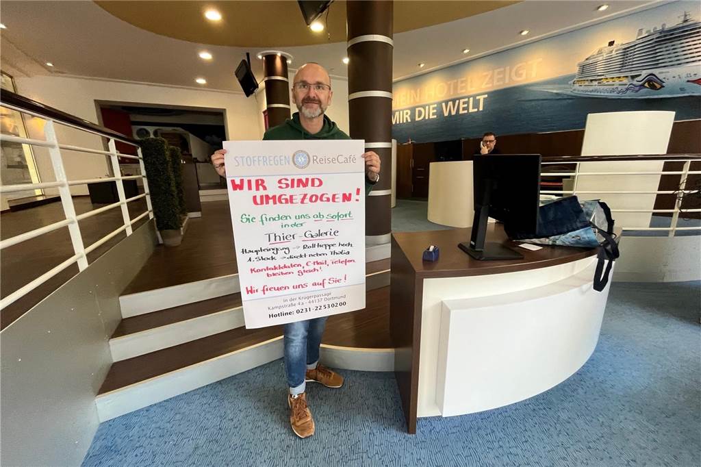 Letzte "Amtshandlung" an der Kampstraße in Dortmund: Michael Draeger hängt noch das Plakat mit dem Hinweis über den Umzug in die Thier-Galerie in die Eingangstür. Seit 2009 war das Reisebüro Stoffregen am Eingang zur Krüger-Passage zu finden.