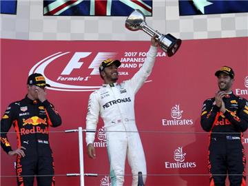 Lewis Hamilton freut sich nach seinem Sieg mit den Red Bull-Fahrern Max Verstappen (l) und Daniel Ricciardo. Foto: Toru Takahashi