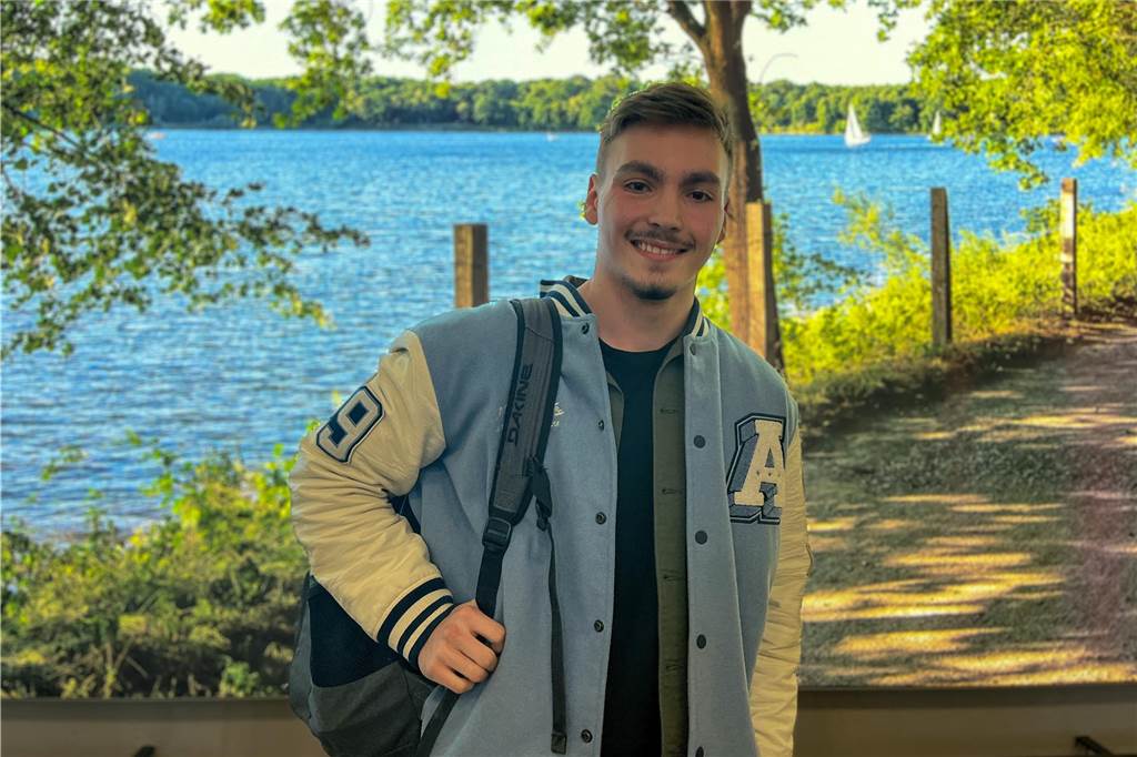 Karrieresprung mit Hauptschulabschluss: „Ich konnte mich durchboxen!“ Luc steht vor einer Leinwand, die den Halterner Stausee zeigt.