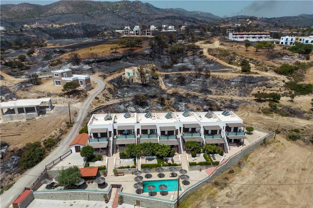 Griechenland verspricht kostenlosen Urlaub: Entschädigung für Rhodos-Touristen Luftaufnahme einer Ferienanlage auf Rhodos mit Waldbrand-Spuren im Hintergrund,