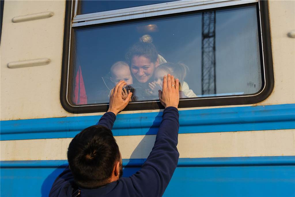 Ein Jahr Krieg in der Ukraine: Diese Orte und Geschehnisse sind besonders in Erinnerung geblieben Ein Mann gestikuliert vor einem Zug nach Polen am Bahnhof von Lwiw zu seiner Familie.