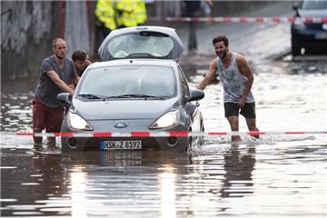 Männer schieben am 19.07.2017 ein Auto aus dem Wasser einer überfluteten Straße in Köln (Nordrhein-Westfalen). In Köln hatte es zuvor ein starkes Gewitter gegeben. 