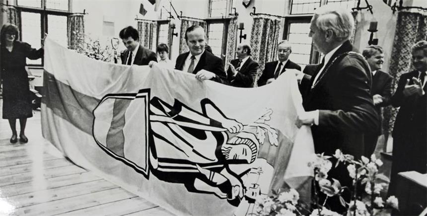 25 Jahre Städtepartnerschaft werden gefeiert März 1990: Während einer Sonderratssitzung am 24. März 1990 im Saal des Alten Rathauses in Werne begründen Vertreter beider Städte offiziell die Partnerschaft. Bürgermeister Willi Lülf (r.) überreicht die Werner Stadtfahne seinem Amtskollegen Jürgen Olagemann(4. v. l.) und dessem Stellvertreter Uwe Berndt (2. v. l.).