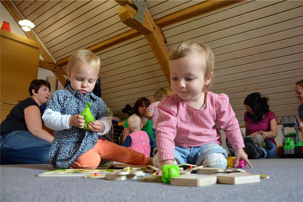 Wenn der Nachwuchs sich nicht drehen will: Jedes Kind ist anders Kinder sitzen auf einem Boden und spielen mit Spielzeug
