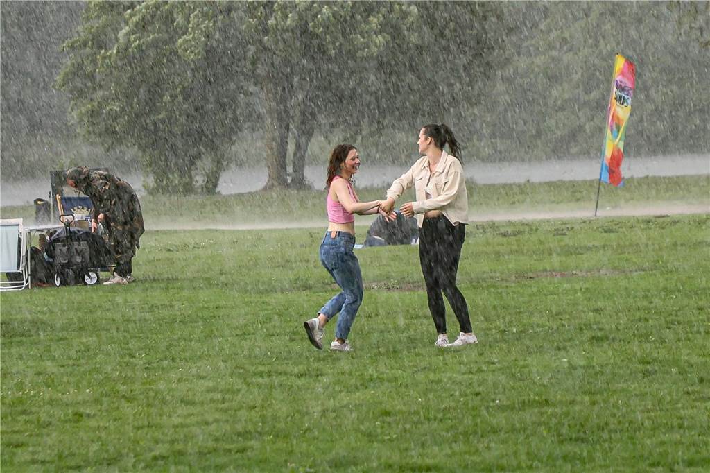 Manchen Besuchern scheint der Regenguss gar nichts auszumachen. Die beiden jungen Frauen tanzen einfach weiter.