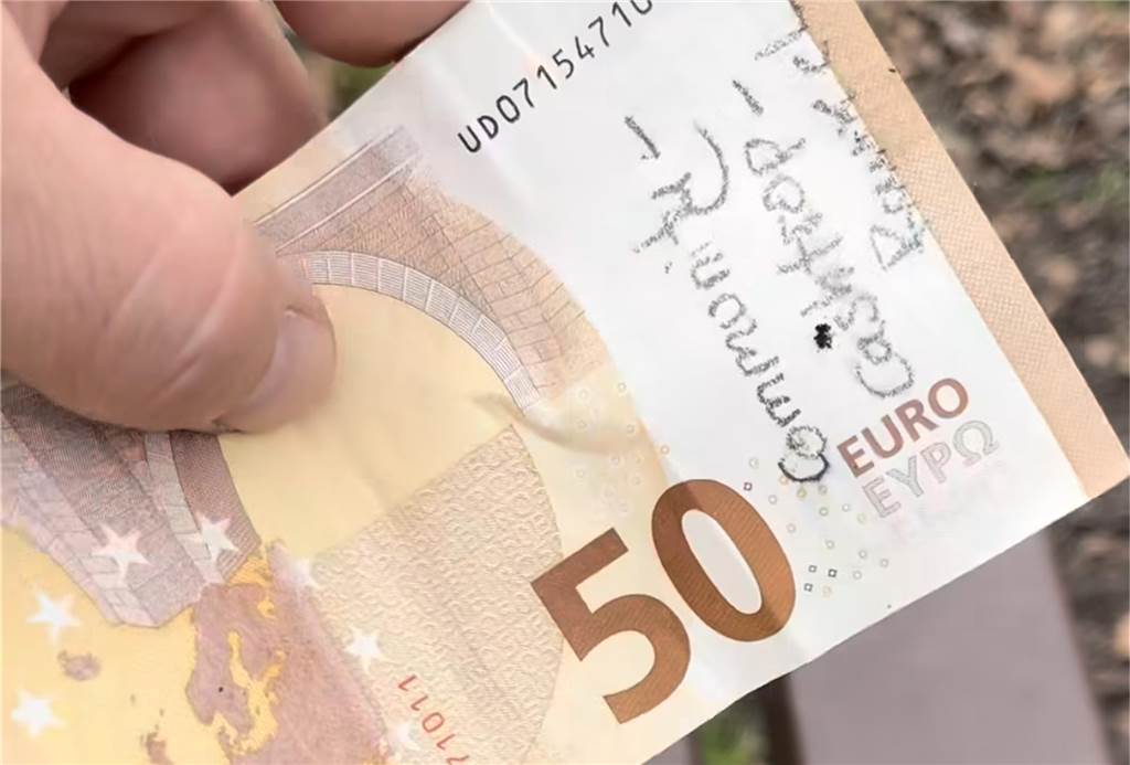 Verstecktes Geld in der Stadt soll Menschen Freude bereiten Dennis hält einen beschrifteten 50 Euro Schein in der Hand und will ihn verstecken.