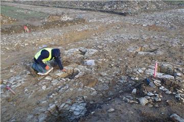 Mann kniet neben Siedlungsresten aus der Jungsteinzeit. Foto: E. Manz/LWL/Archäologie am Hellweg e.G