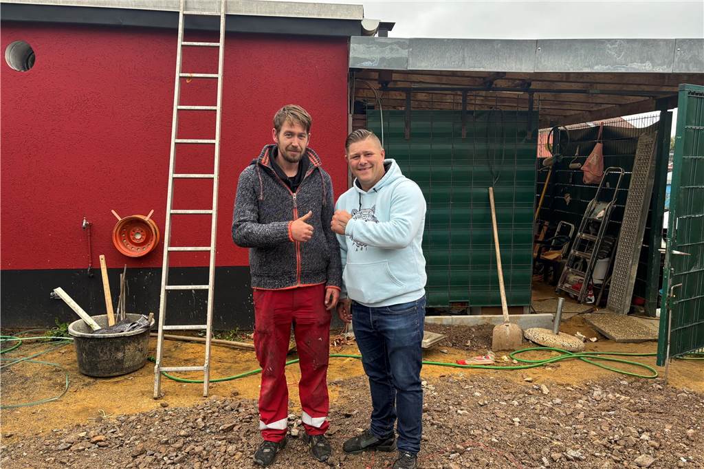 Marcel Smuda und Timur Ratzer stehen nebeneinander neben dem Grillhaus, wo der Biergarten entstehen soll. Smuda hilft bei den notwendigen Arbeiten.