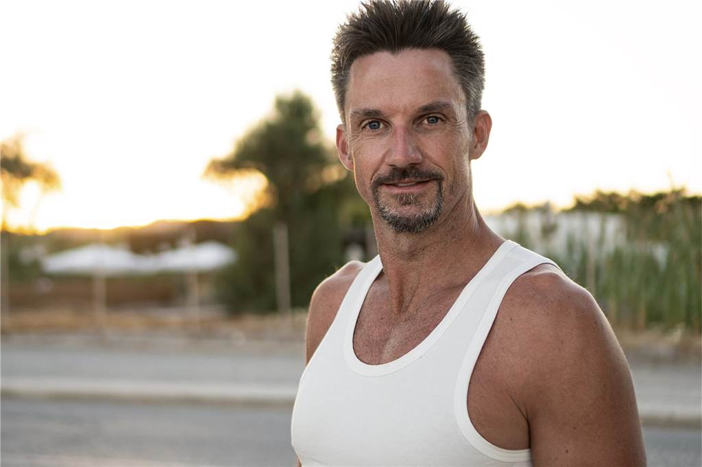 Dortmunder ist raus bei GNTM: Mark (48) vergießt Tränen vor der Kamera Mark Lewandowski – Teilnehmer bei GNTM 2025 – steht im Tanktop vor der Kamera und lächelt leicht.