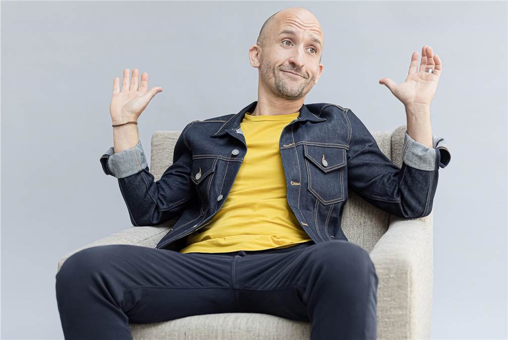 Kabarett und Comedy in der Seestadt: Der Kulturboitel meldet sich zurück Markus Barth sitzt auf einem Stuhl und guckt lustig.