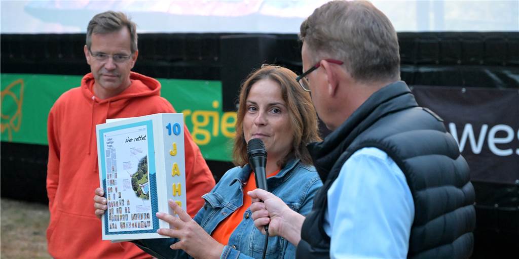Zehn Jahre Bürgerfreibad Selm: „Sind für Zukunft positiv gestimmt“ Markus Jungeilges (links) bekam beim Open Air Kino im Selmer Freibad einen Ordner mit Bildern, Artikeln und Danksagungen aus den letzten zehn Jahren überreicht.