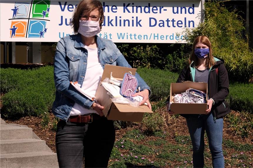Hannah Iserloh, Pressesprecherin der Vestische Kinder- und Jugendklinik Datteln (l.) nimmt über 200 Masken von der ehrenamtlichen Kurierfahrerin Lilli Prinzen entgegen. 
