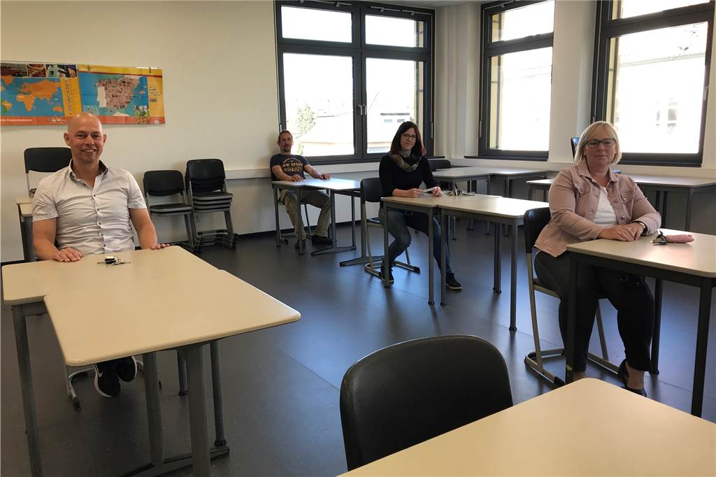 Matthias Bomba (l.) und Kathrin Ollas (2.v.r.) demonstrieren mit Hausmeister Carsten Szech und Sekretärin Heike Schober, wie die Schüler in einem Klassenraum sitzen sollen.