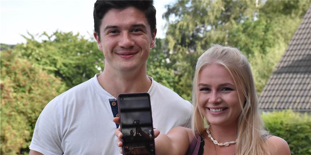 „Super-Fans“ fielen KIZ beim Juicy Beats auf: Mit Fabian hat Gina überall die beste Sicht Die Cheerleader Gina und Fabian halten ein Handy mit dem Tiktok-Video von KIZ, auf dem sie zu sehen sind.