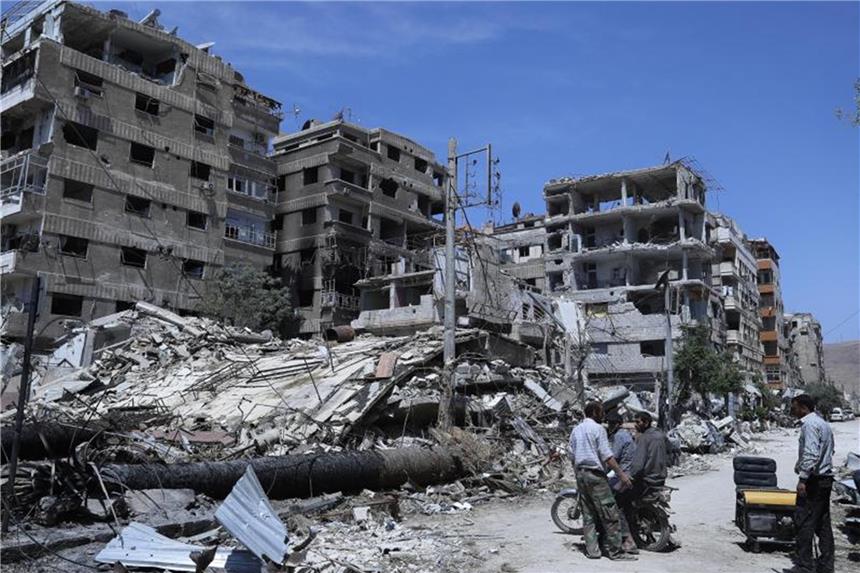 Schüsse auf UN-Team in Duma: Ermittlungen der OPCW stocken Menschen stehen vor zerstörten Gebäuden in Duma. Hier soll ein mutmaßlicher Chemiewaffenanschlag passiert sein. Foto: Hassan Ammar/AP