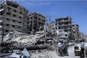 Menschen stehen vor zerstörten Gebäuden in Duma. Hier soll ein mutmaßlicher Chemiewaffenanschlag passiert sein. Foto: Hassan Ammar/AP