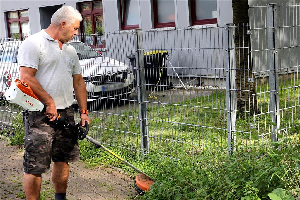 Firmenchefs kritisieren Grünpflege: „Kann so nicht weitergehen“ Michael Nowotnick pflegt mit dem Kantenschneider das Grün am Zaun seiner Firma.