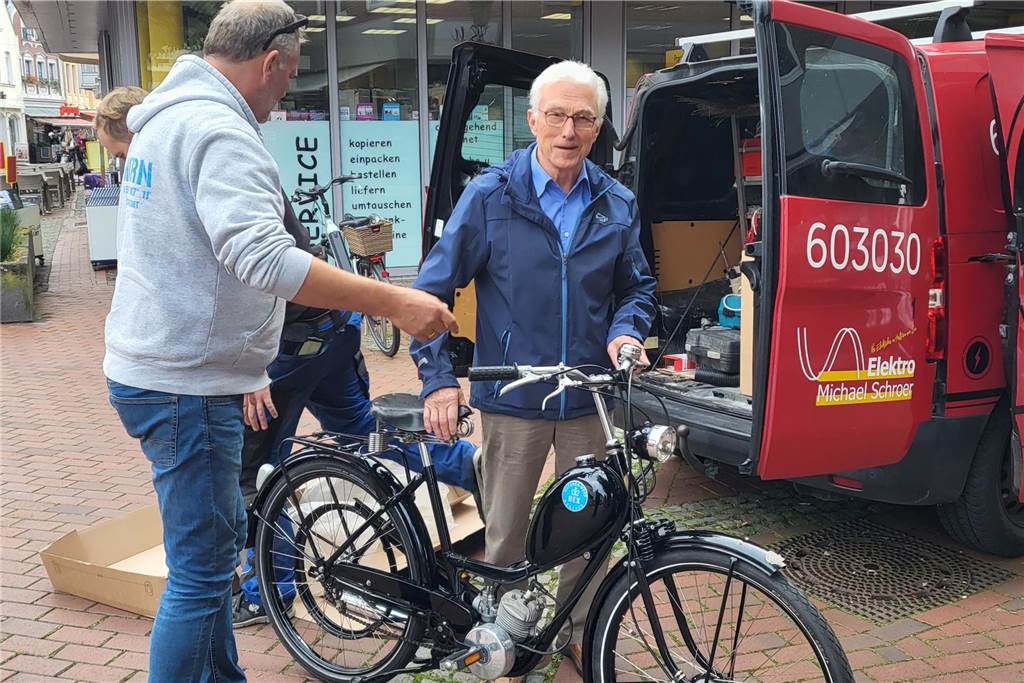 Oldtimer-Moped steht jetzt im Schaufenster in der Innenstadt Zwei Männer laden einem Moped aus einem Lieferwagen.