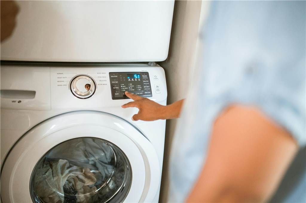 Waschmaschine stinkt: Gründe, Hausmittel und Tipps zusammengefasst Ein Mann schaltet die Waschmaschine ein.