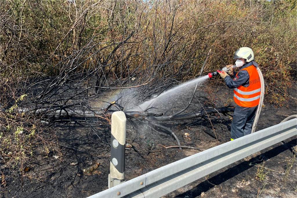 Brandserie: Erneut Feuer an Bundesstraße und Autobahn in Dorsten Ein Feuerwehrmann löscht einen Böschungsbrand.