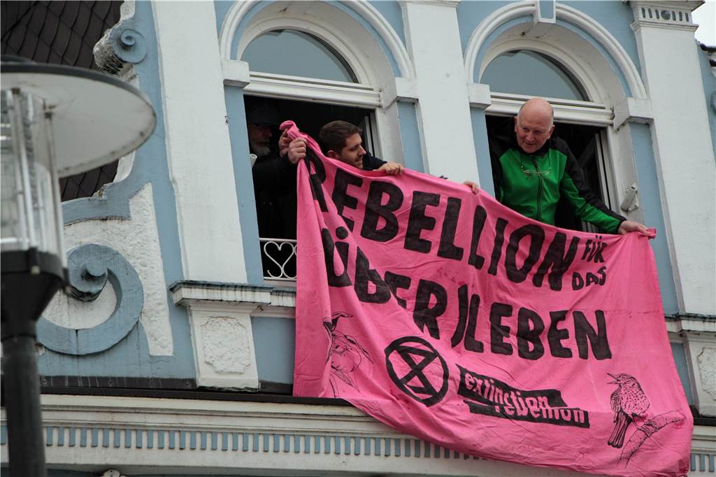 Darum schauten die Wochenmarkt-Besucher am Freitag zum Hussel-Haus hoch Mit einem Banner sowie einer kurzen Megafon-Ansprache machten die Aktivisten von Extinction Rebellion (Rebellion für das Über-Leben) auf ihr Anliegen aufmerksam.