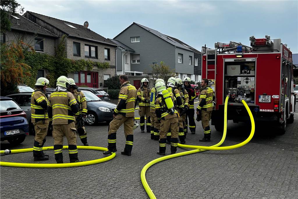 Feuerwehr Haltern löscht Wohnungsbrand Feuerwehrleute an einem Feuerwehrwagen.