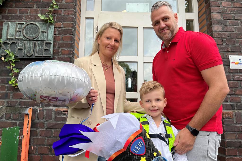 Mit Luftballon und Schultüte im Weltall-Design freuen sich Levi und seine Eltern Julia und Markus Baron über die Einschulungsfeier.
