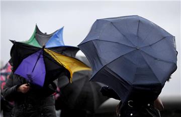 Mit strapazierten Regenschirmen kämpfen sich die Menschen durch die Region. 