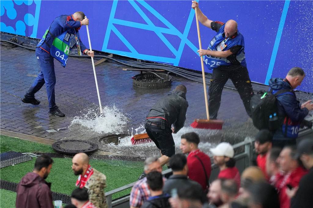 Straßen, Keller und Bahn-Station überflutet - Feuerwehr zieht Bilanz Mitarbeiter beseitigen im Stadion Wasser, nachdem sie während eines starken Regens vor dem Spiel einen Kanaldeckel entfernt haben.