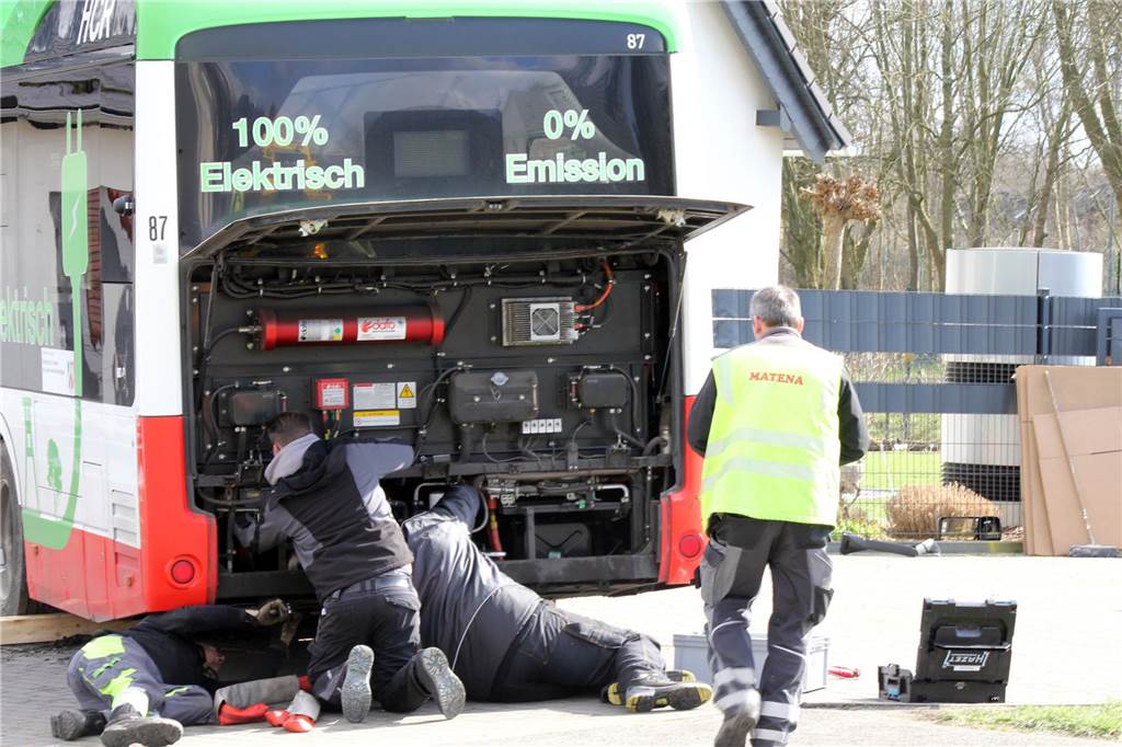 Mitarbeiter des Abschleppunternehmens bereiten den Bus vor. Sie bringen Seile am Heck an.