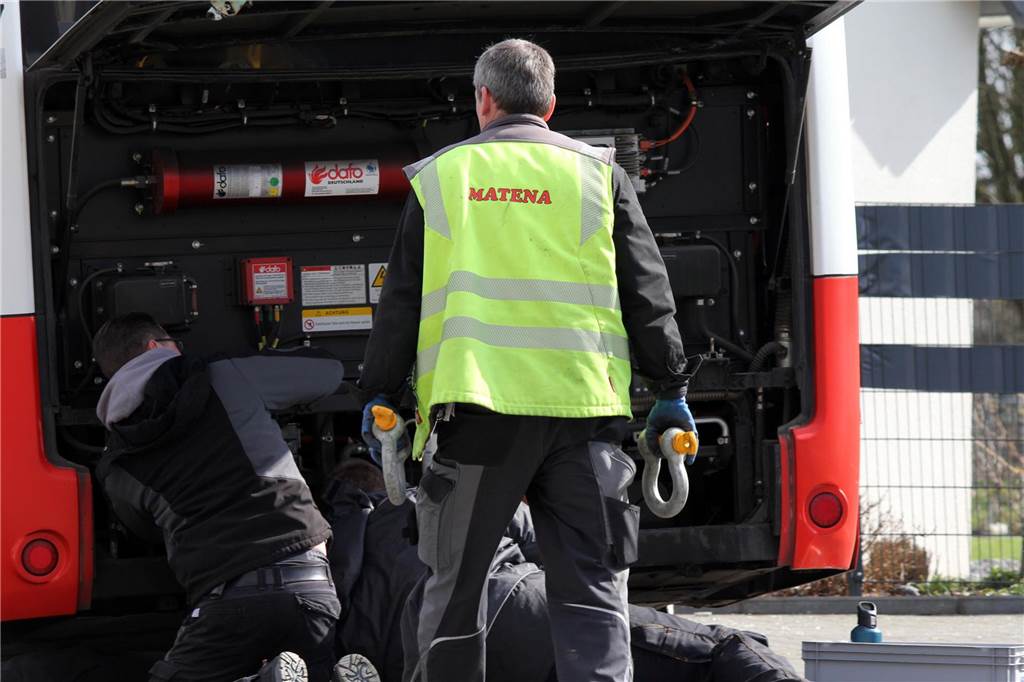 Mitarbeiter des Abschleppunternehmens bringen ein Seil am Heck des verunglückten Elektrobusses an.