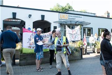 Mitarbeiter des Universitätsklinikums stehen vor dem Eingang der Klinik. Foto: Federico Gambarini/Archiv