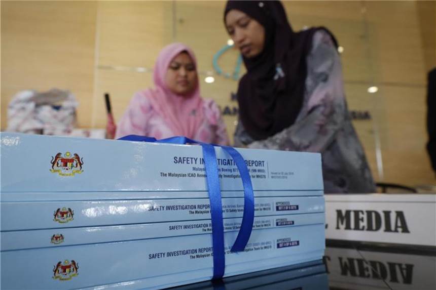 Rätsel MH370 bleibt - Bericht lässt Raum für Spekulationen Mitarbeiter ordnen Kopien des Abschlussberichts nach dem rätselhaften Verschwinden von Flug MH370. Foto: Vincent Thian/AP
