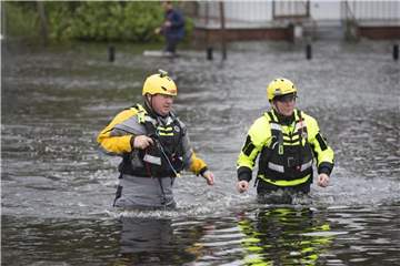 Mitglieder des Greenville Fire Department waten durch eine überflutete Straße. Foto: Robert Willett