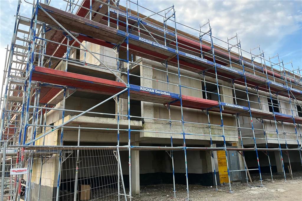 Neue Eigentumswohnungen kurz vor Vollendung: Das bieten und kosten sie Blick auf ein im Bau befindliches Mehrfamilienhaus am Dietrich-Bonhoeffer-Weg in Herten, das von Baugerüsten umhüllt ist.