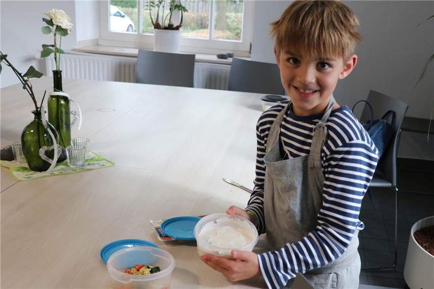Kinder-Koch-Klub mit Frischkorn-Müsli, Rührei mit Paprika und einem Quadrat auf dem Boden Moritz (8) mit von den Kindern gemachten Essen. Den Obstquark und das Rührei mit Gemüse. nimmt er mit nach Hause.