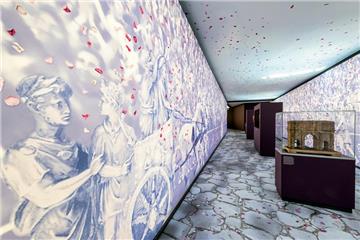 Motive antiker Triumphzüge zieren die Wände der Ausstellung im Römermuseum Haltern. Die Rosenblätter auf der Decke und auf beiden Seiten sind aufgedruckt, ebenso wie die Steine auf dem Boden.