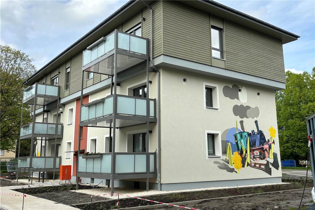 Umzug ums Eck: Monika Franzen lebt seit 55 Jahren im Quartier Ausgekofferte Grünflächen zwischen gepflasterten neuen Zuwegungen an einem sanierten Haus am Walkmühlenweg in Huckarde. Auf der Fassade ist einer Dampflokomotive zu sehen.